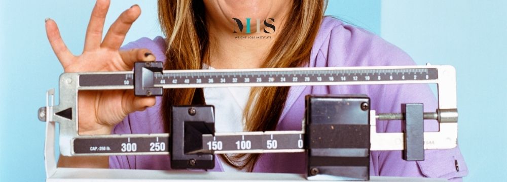 Woman checks her weight on the scale as she celebrates her progress with the MIIS Weight Loss Institute Jump Start Program
