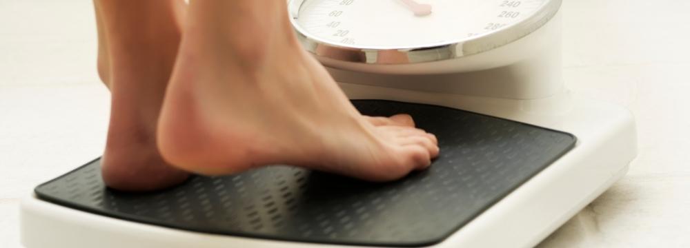 Woman steps on bathroom scale to check weight after bariatric surgery