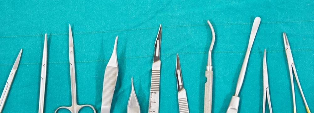 surgical instruments lined up on teal fabric