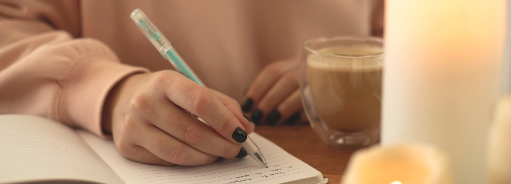 Woman journaling her weight loss journey while drinking coffee