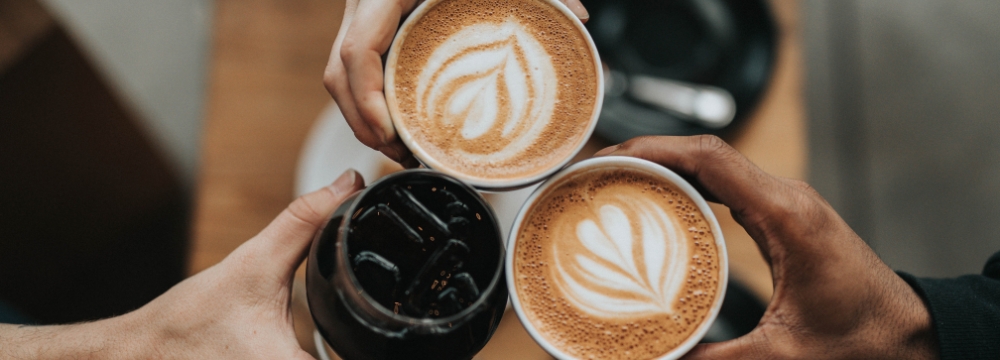 three people holding their coffee cups together