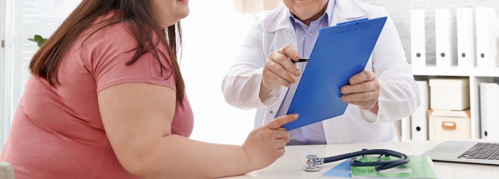 Woman discussing gastric sleeve versus gastric bypass with doctor holding a clipboard